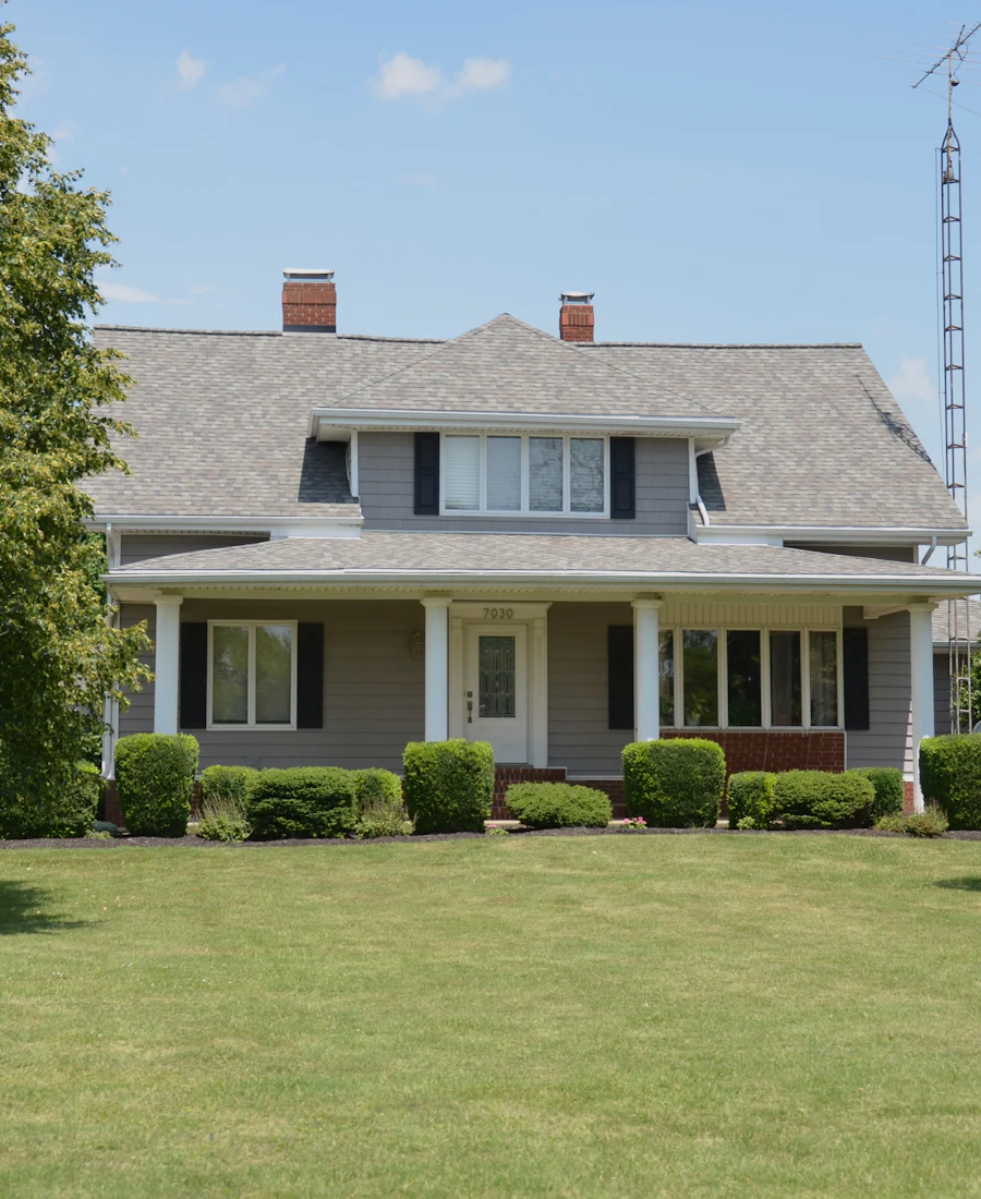 Two story home with a covered porch and a green front lawn